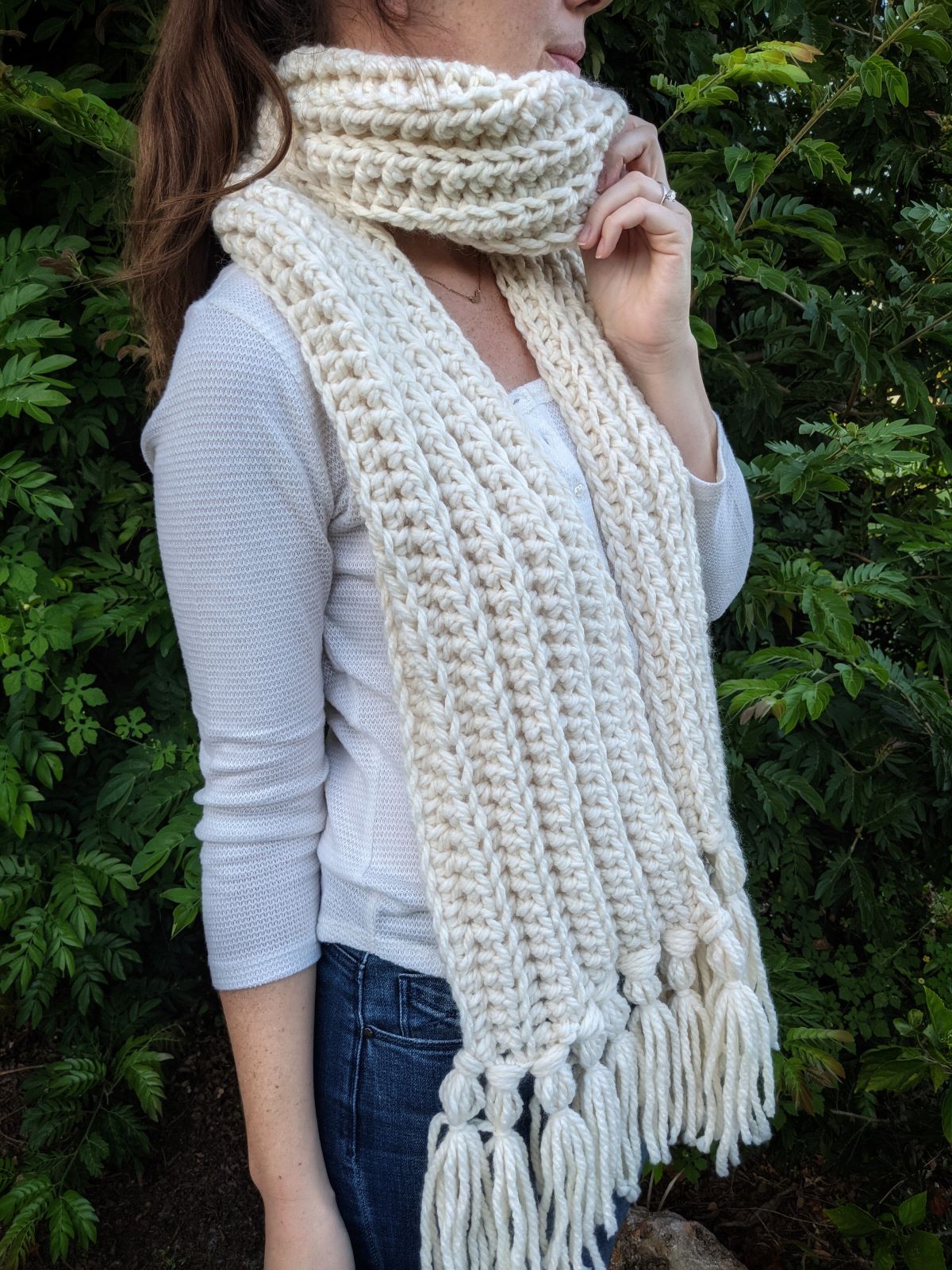 model is wearing a chunky natural colored crochet scarf with a pair of jeans and a long sleeve top