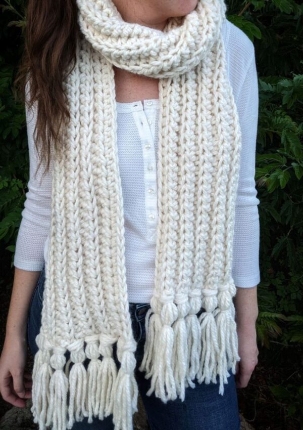 model is wearing a double thick chunky crochet scarf with tassels