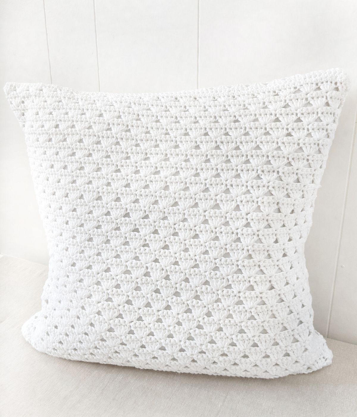 A modern crochet pillow cover with a white background