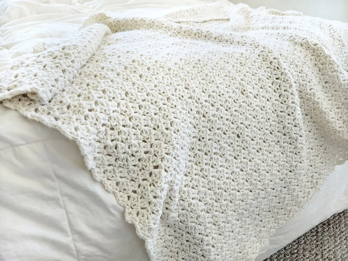 white cotton one-stitch repeat crochet blanket pattern on bed