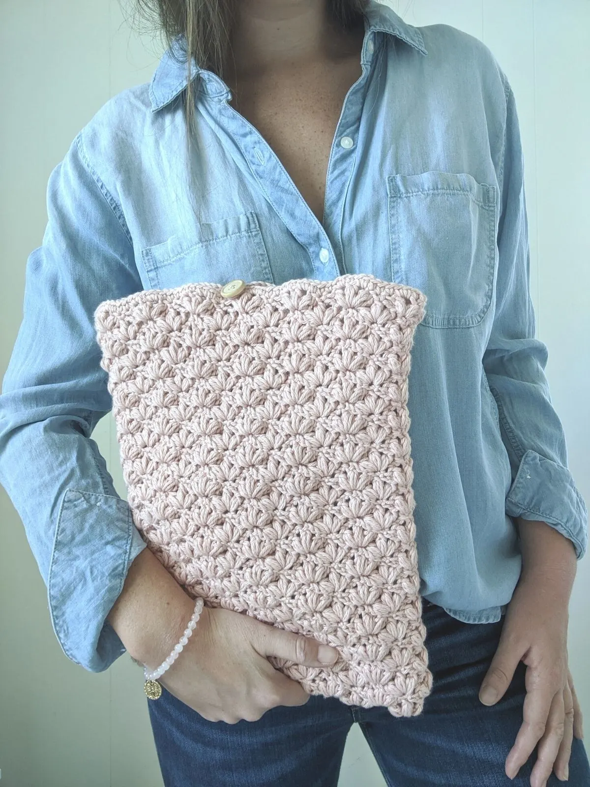 model is holding a crochet laptop case that is made with the lotus stitch in her left hand.
