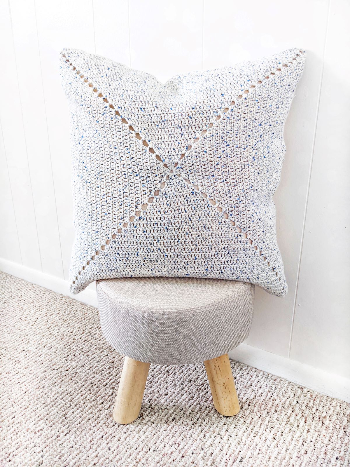 a cotton double crochet granny square cushion cover pillow on a mini wooden stool
