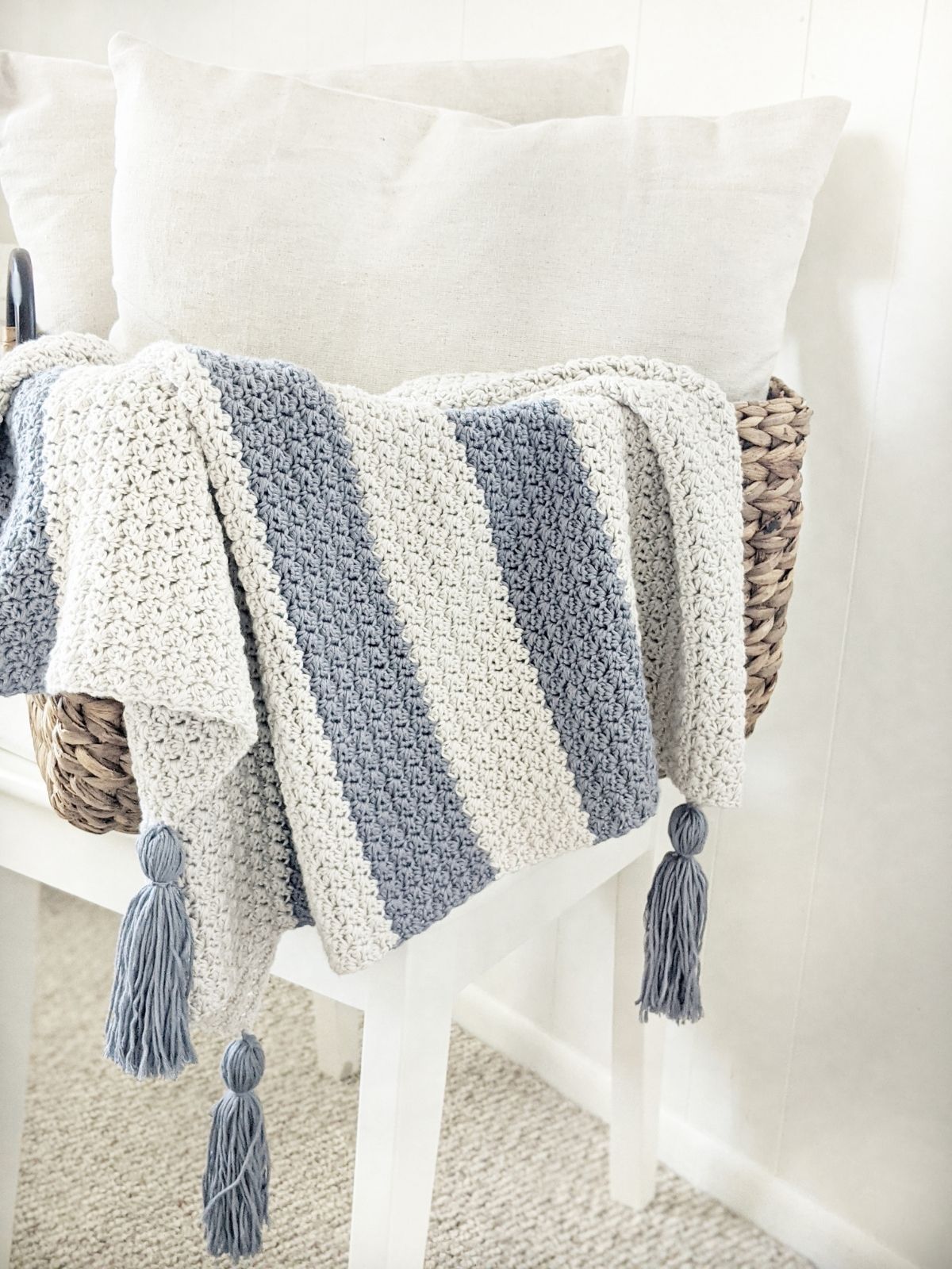 a folded striped crochet baby blanket in a basket