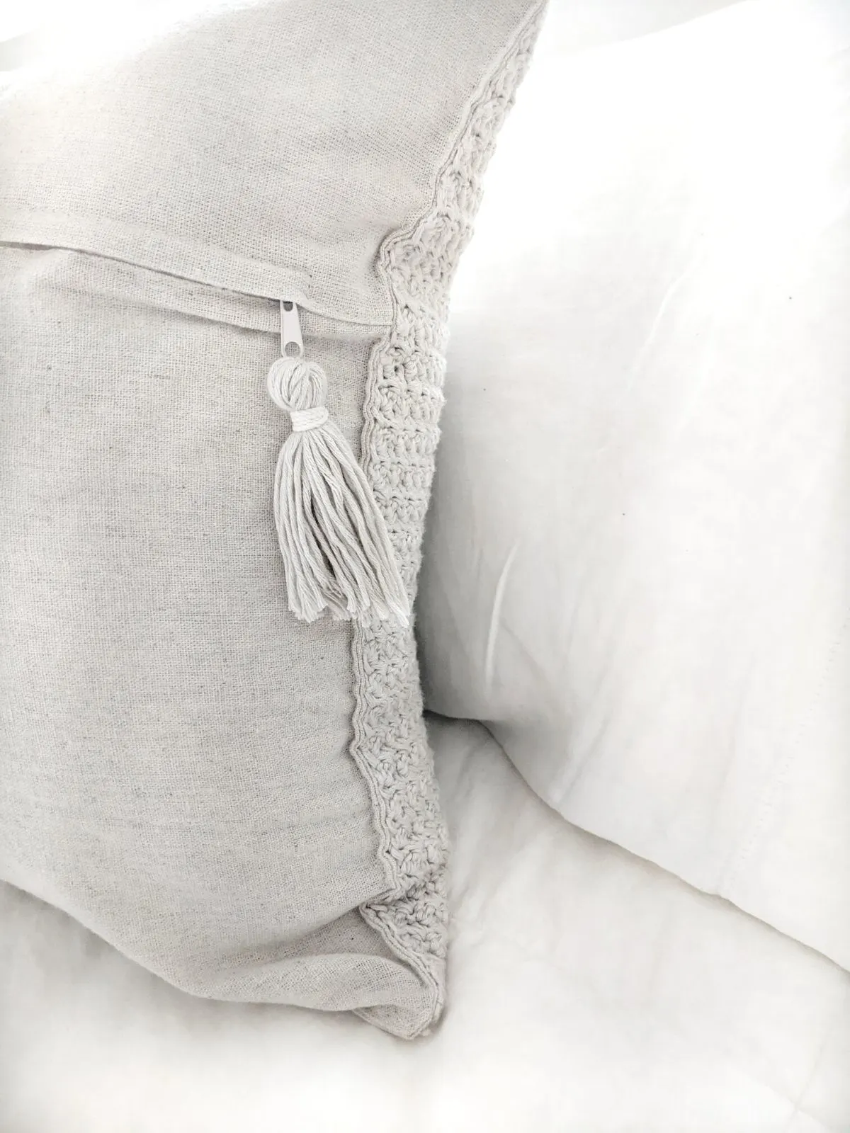 The back of a crochet pillow cover with a hanginig tassel. 