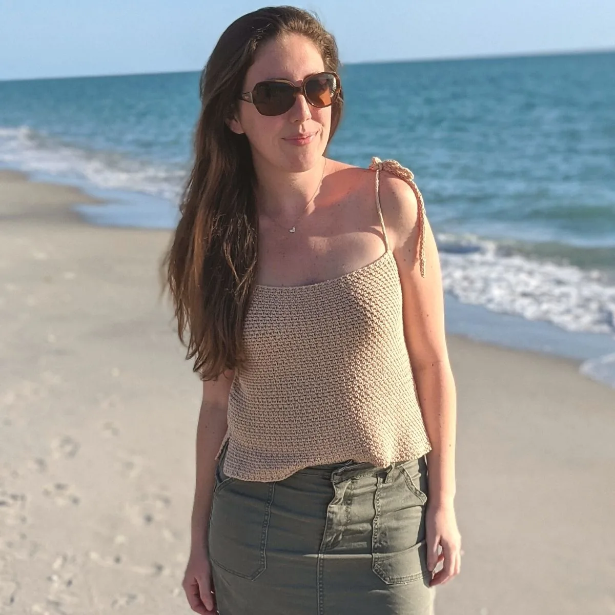 Model is wearing a sleeveless crochet summer top on the beach.