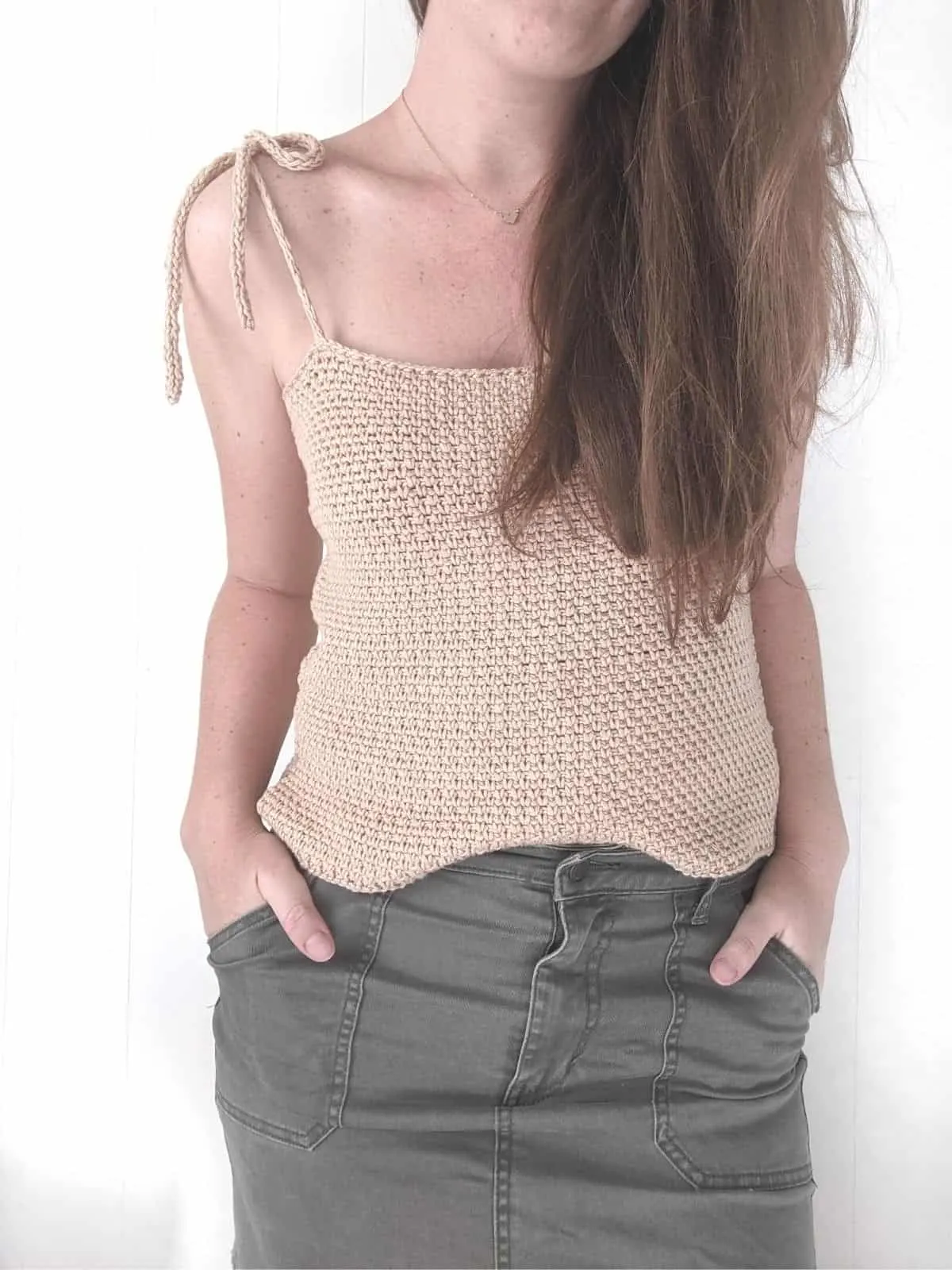 model wearing a sleeveless crochet top with a skirt.