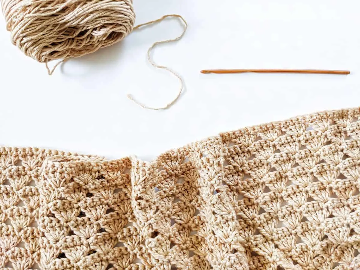 a progress photo showing how to make the shell stitch with a wooden crochet hook