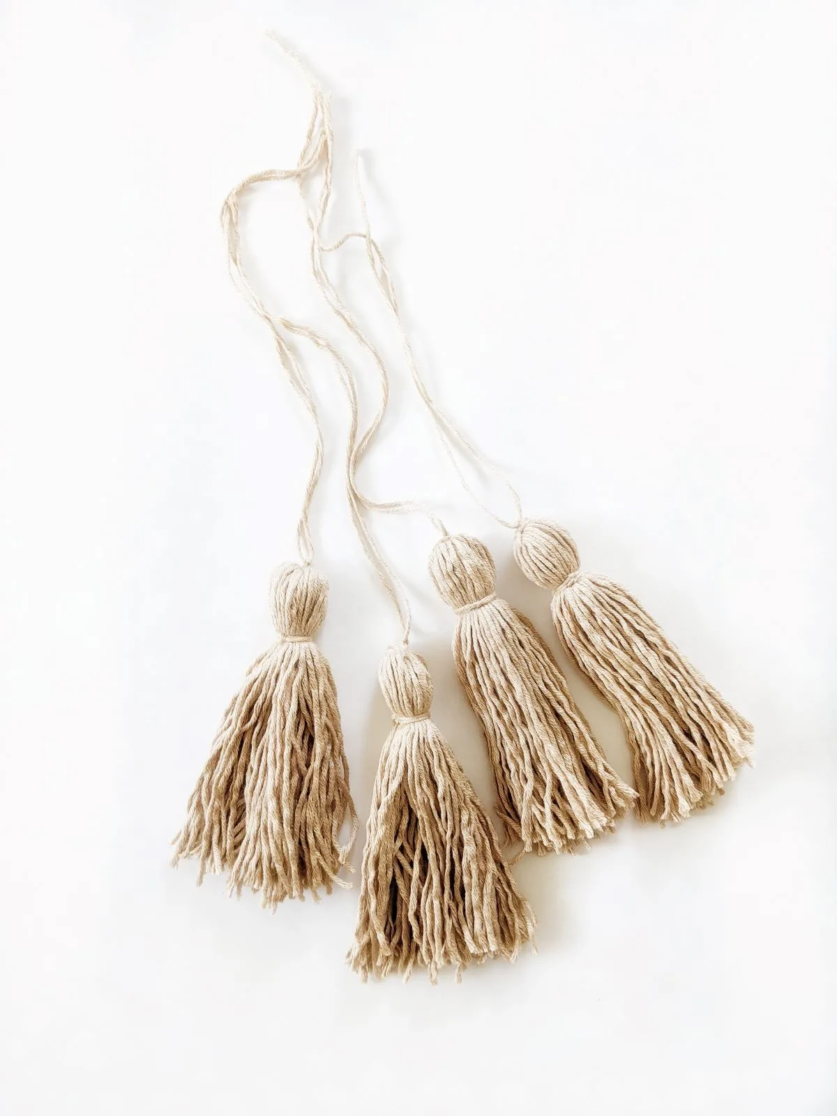 4 handmade tassels on a white surface using Lion Brand Coboo yarn