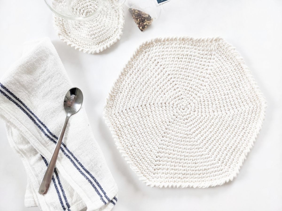 a cotton crochet placemat pattern with a matching crochet coaster on a white surface