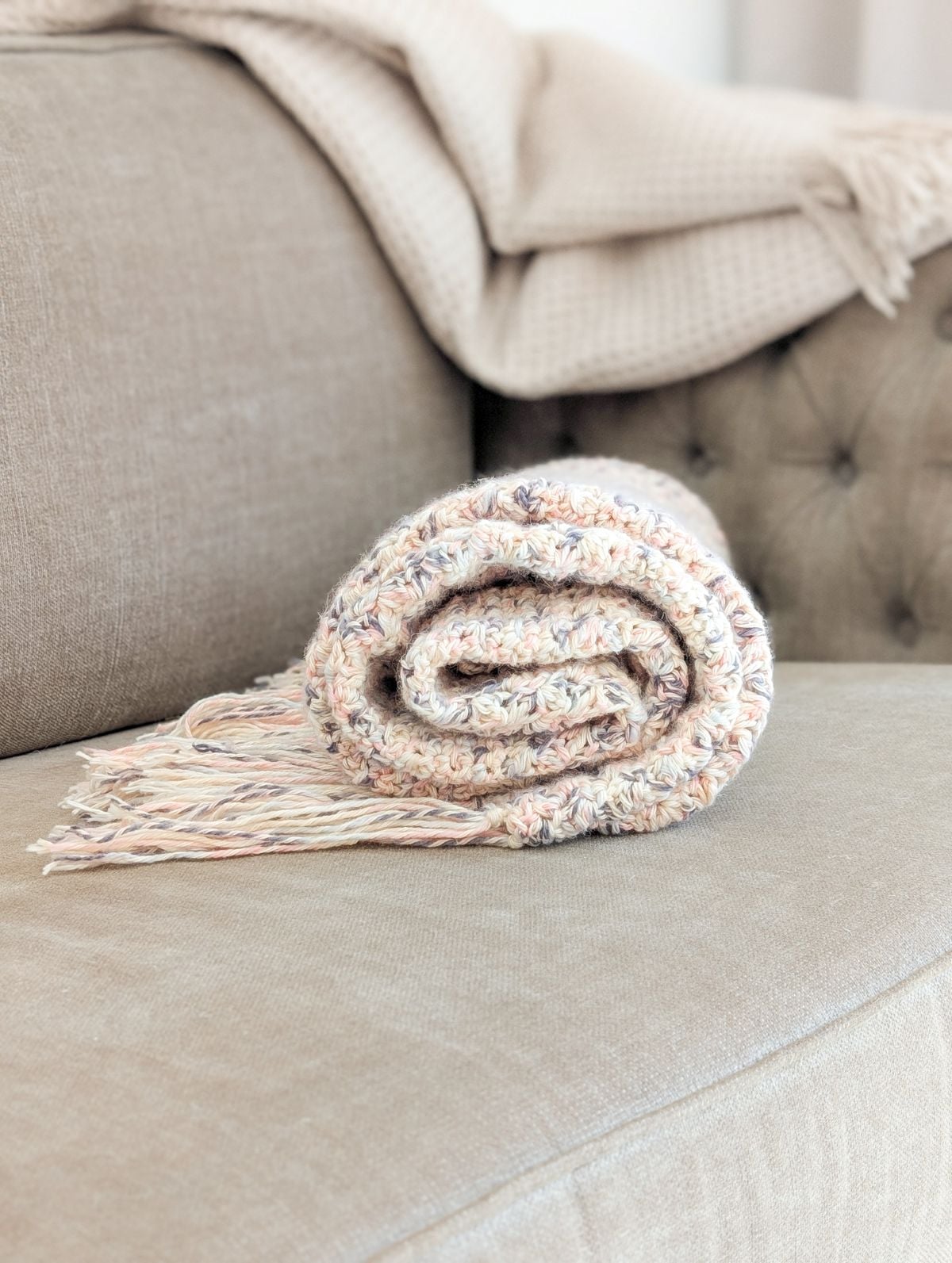 A rolled up crochet blanket on the couch.