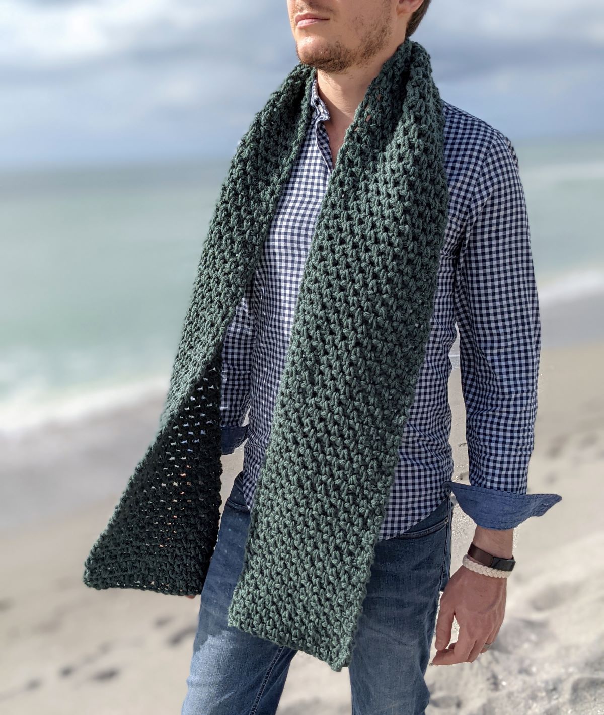 model is wearing an oversized textured classic men's crochet scarf pattern in the color Juniper by Hue + Me yarn