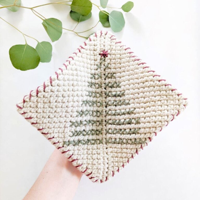 A crochet potholder with a Christmas tree embroidered on it.