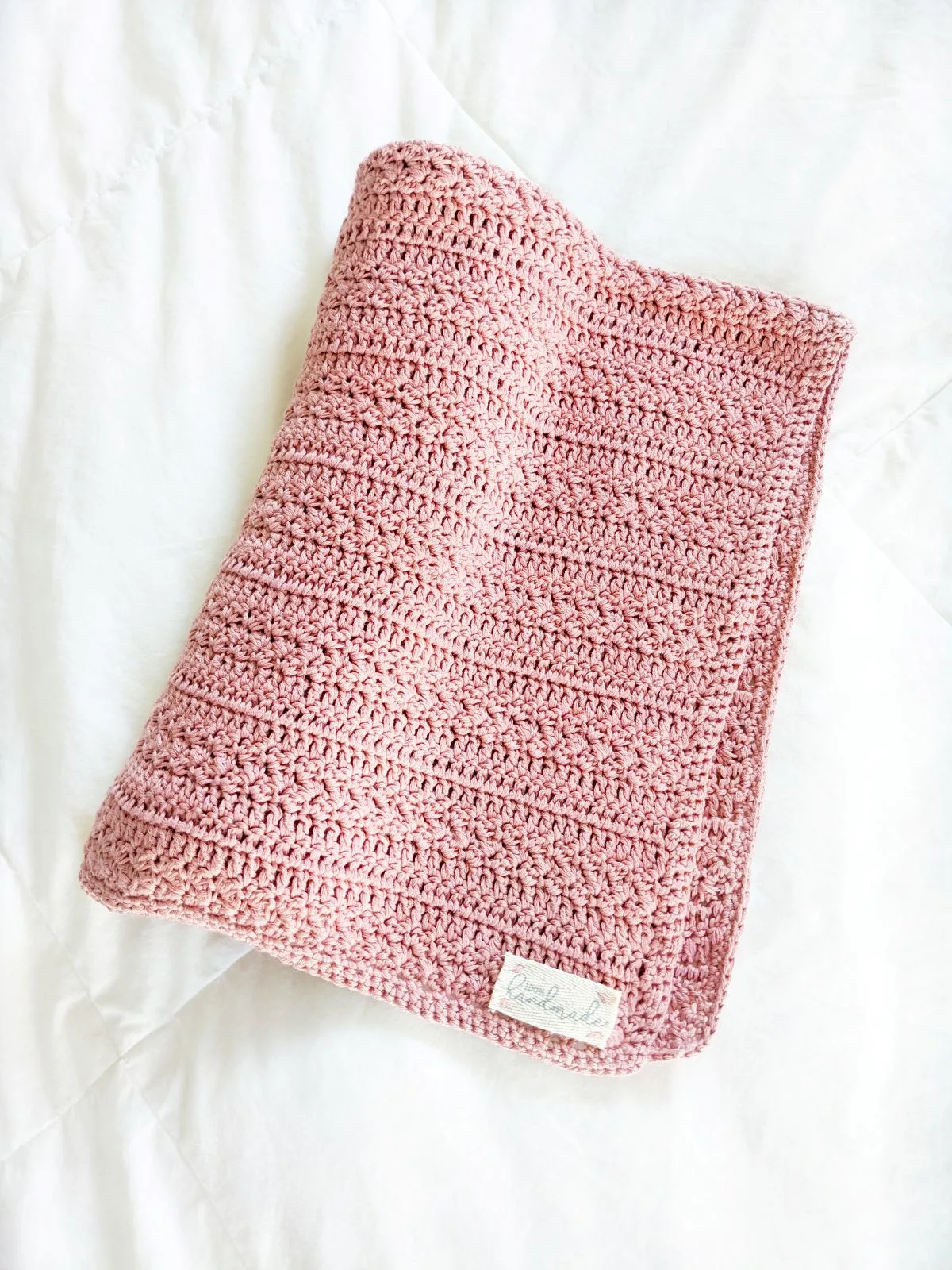 a folded cotton crochet baby blanket a white surface