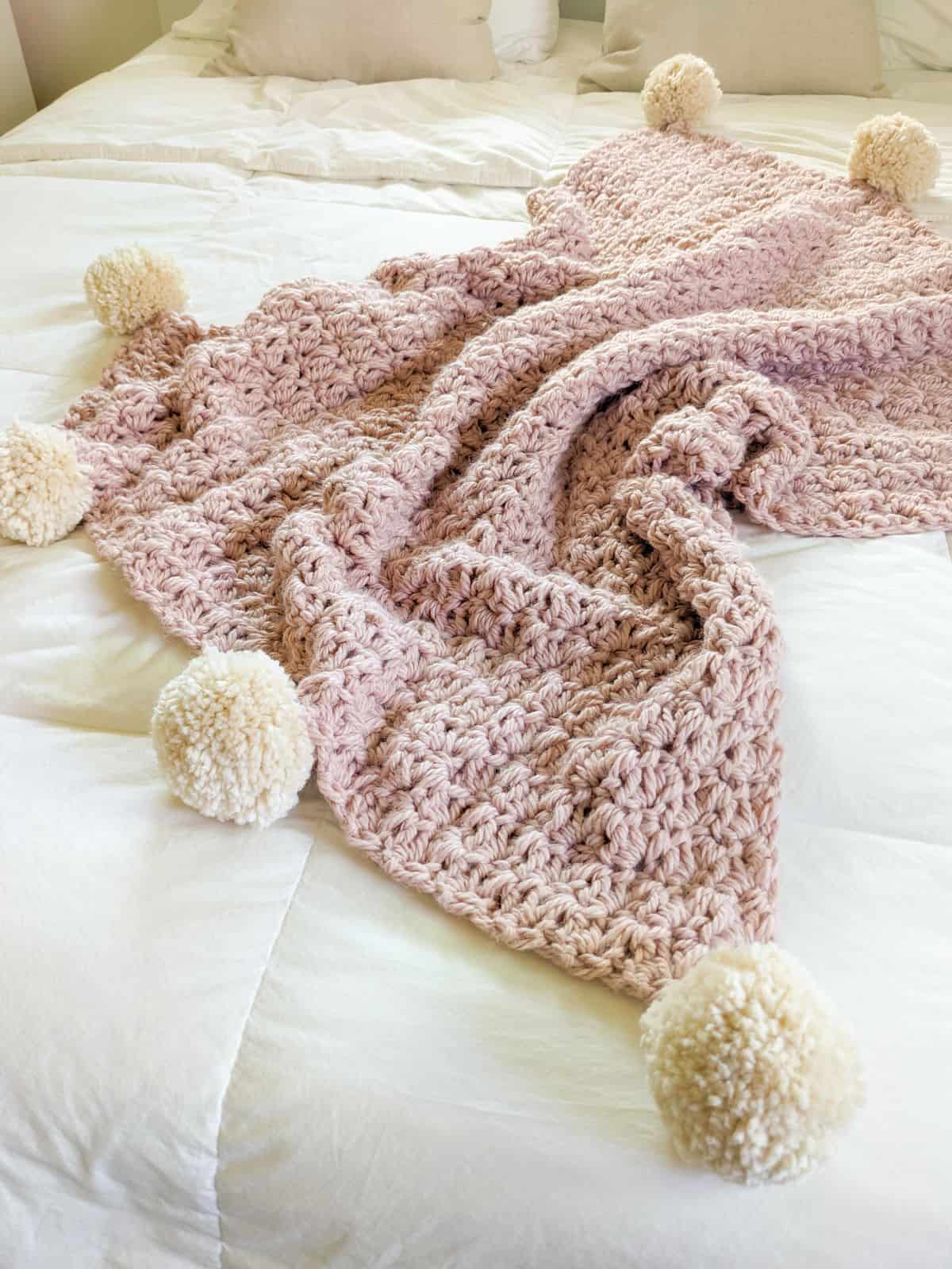 A chunky bulky weight crochet blanket with pom-poms. 
