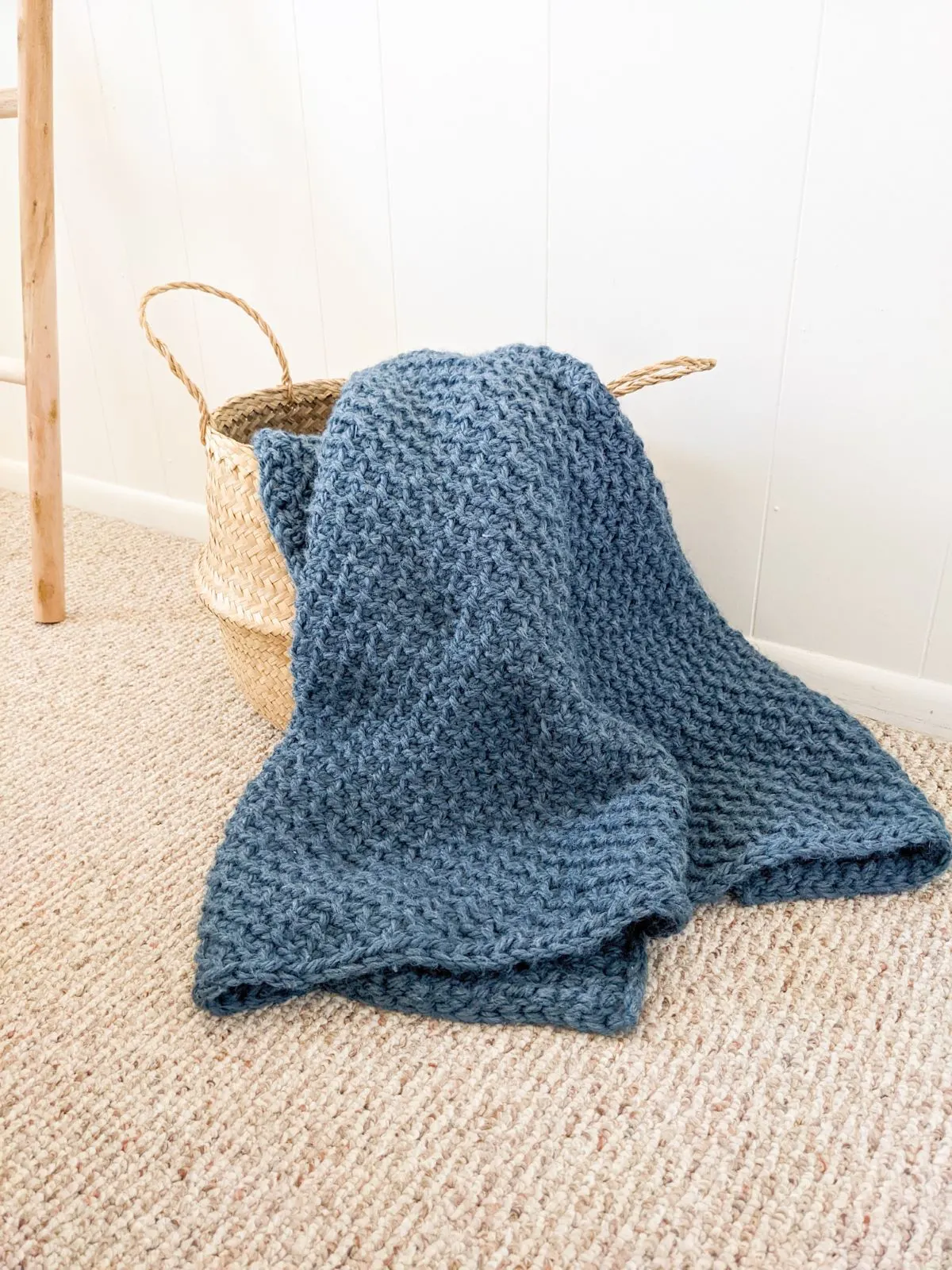 A folded blue crochet blanket in a belly basket. 