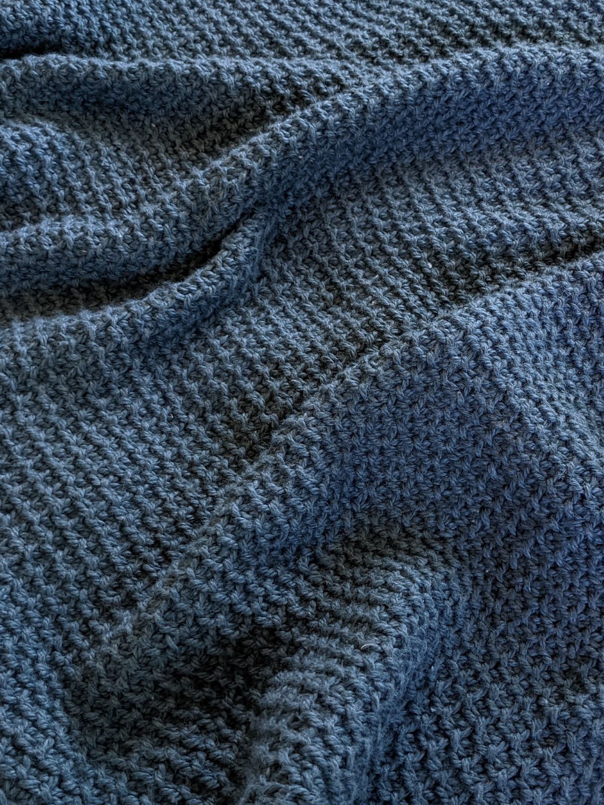 An up close look at the Tunisian crochet Honeycomb stitch blanket in the color dark blue.
