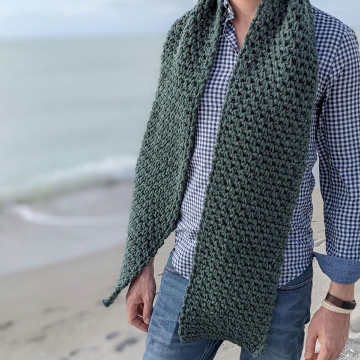 Model is wearing a textured men's crochet scarf pattern.