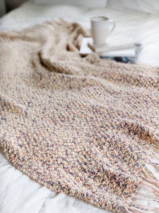 A textured cotton throw blanket with fringe that uses Lion Brand Comfy Cotton Blend Yarn. 