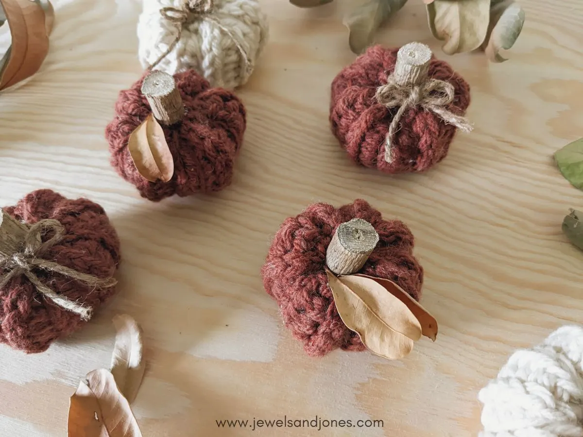 Small crochet pumpkins with decorations on them.