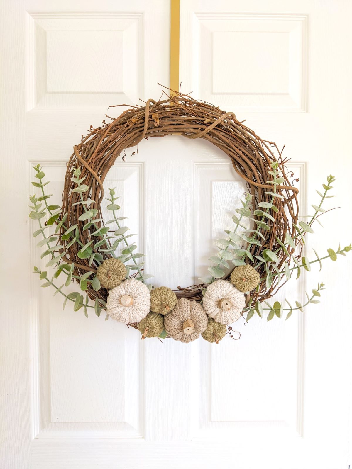 A grapevine wreath with small and medium size crochet pumpkins. 