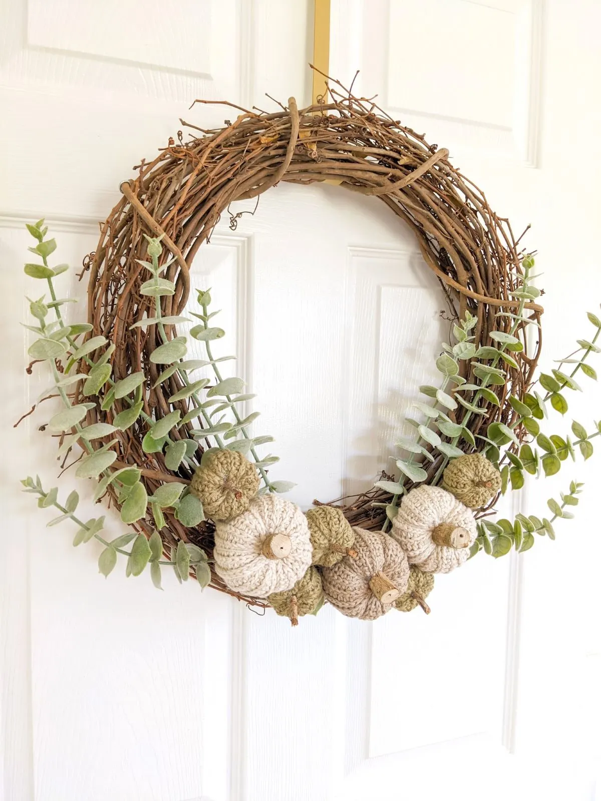 A fall wreath with eucalyptus and crochet pumpkins in 2 different sizes.  
