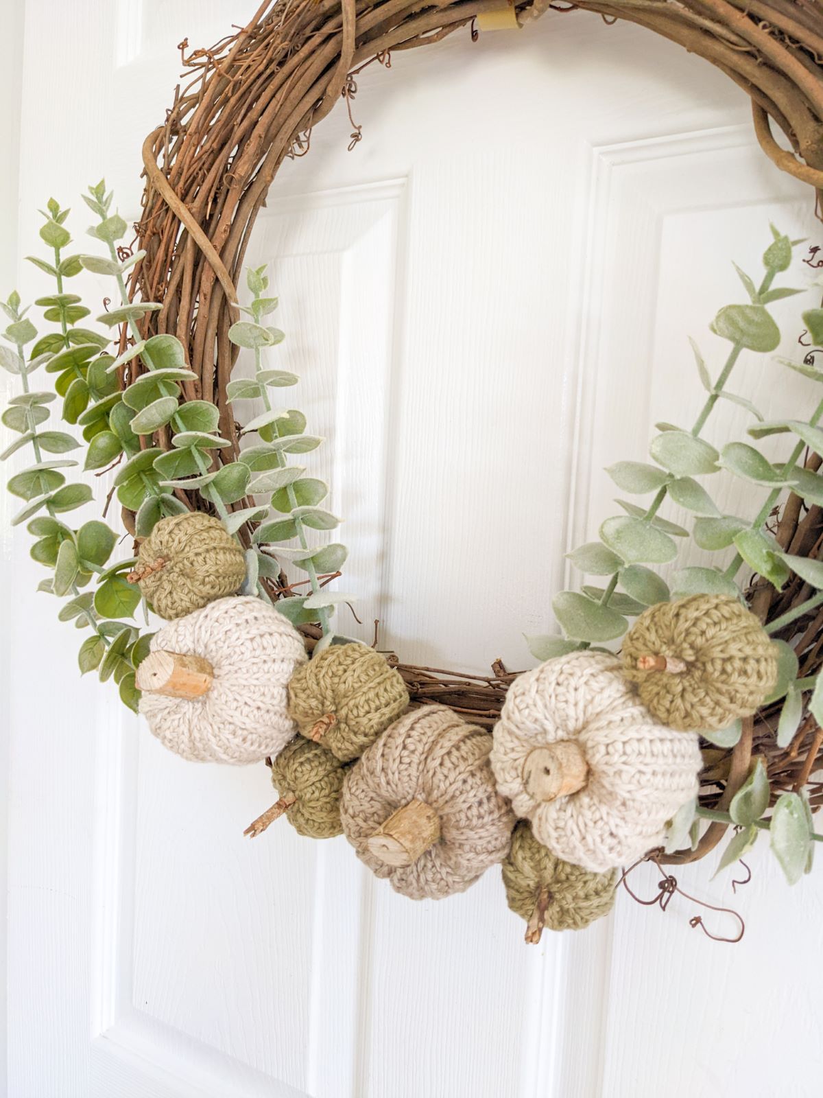 a wreath made from branches that had eucalyptus and small and large pumpkins.  