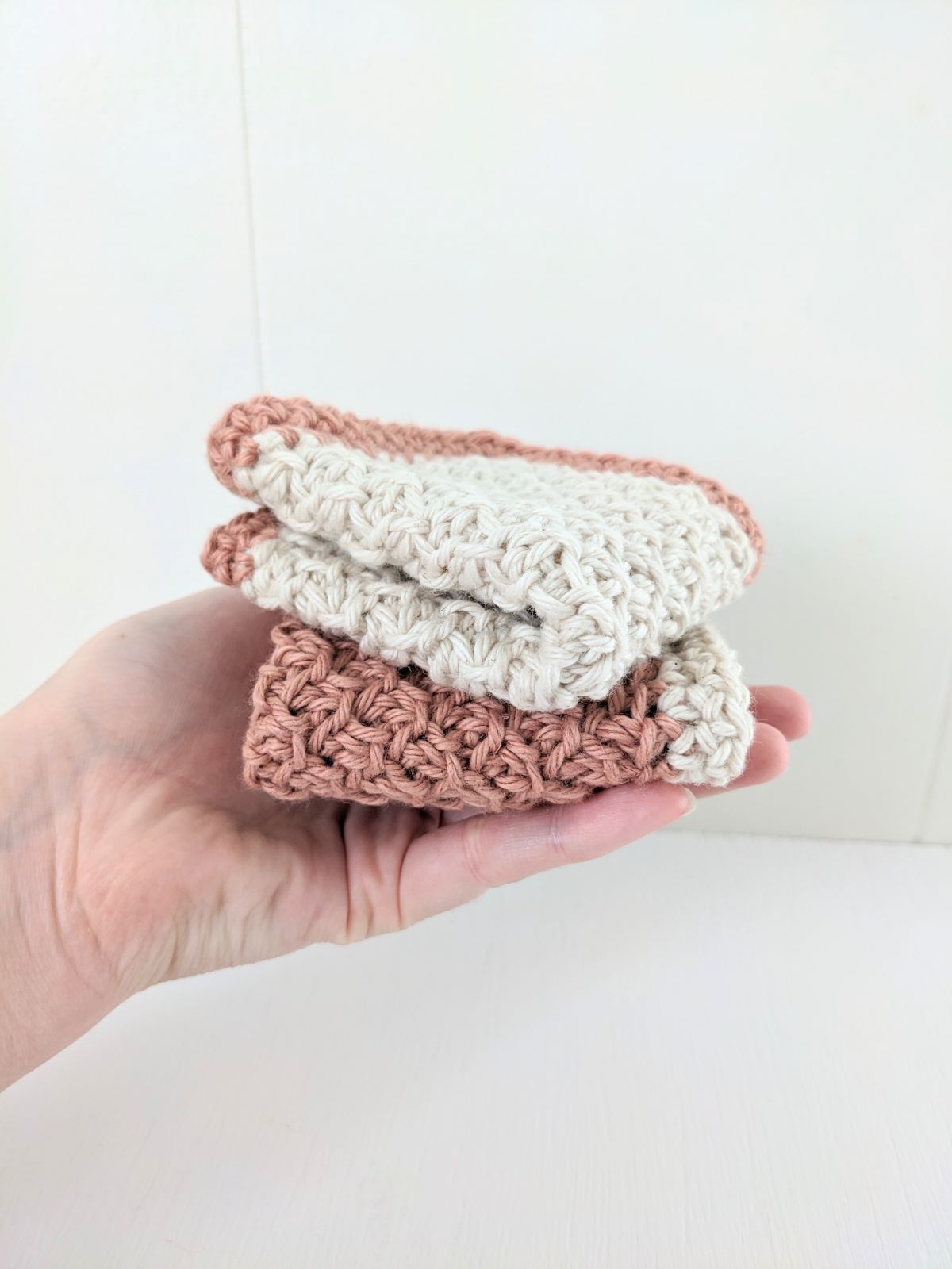 Two folded crochet washcloths that use the honeycomb stitch.
