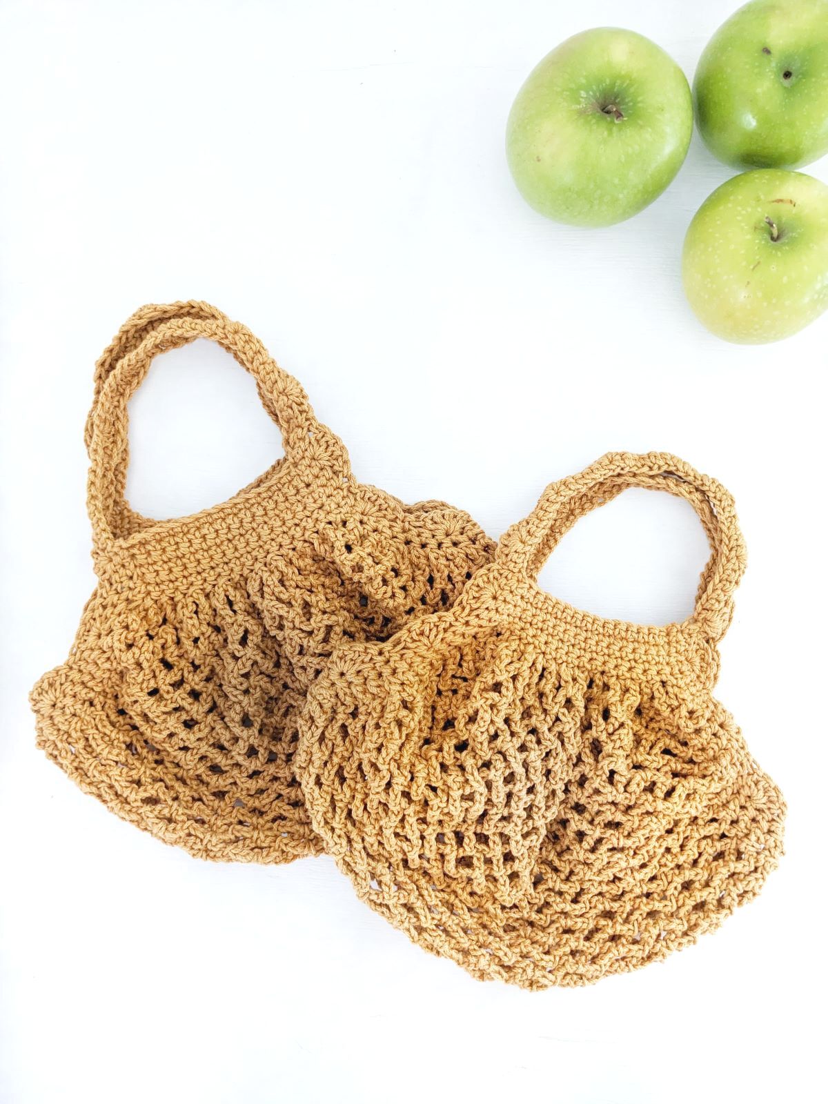 2 small crochet market bags with 3 green apples.