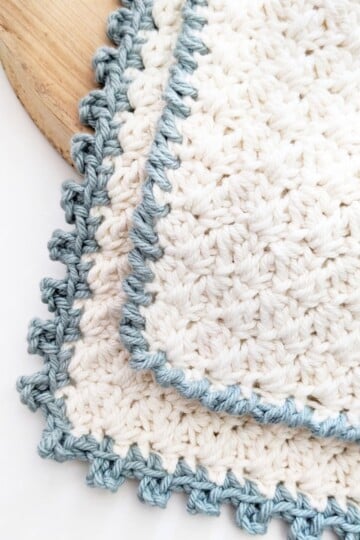 A white cotton crochet washcloth with a picot stitch edge border.