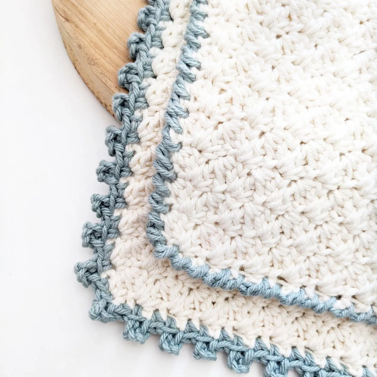 A white cotton crochet washcloth with a picot stitch edge border.