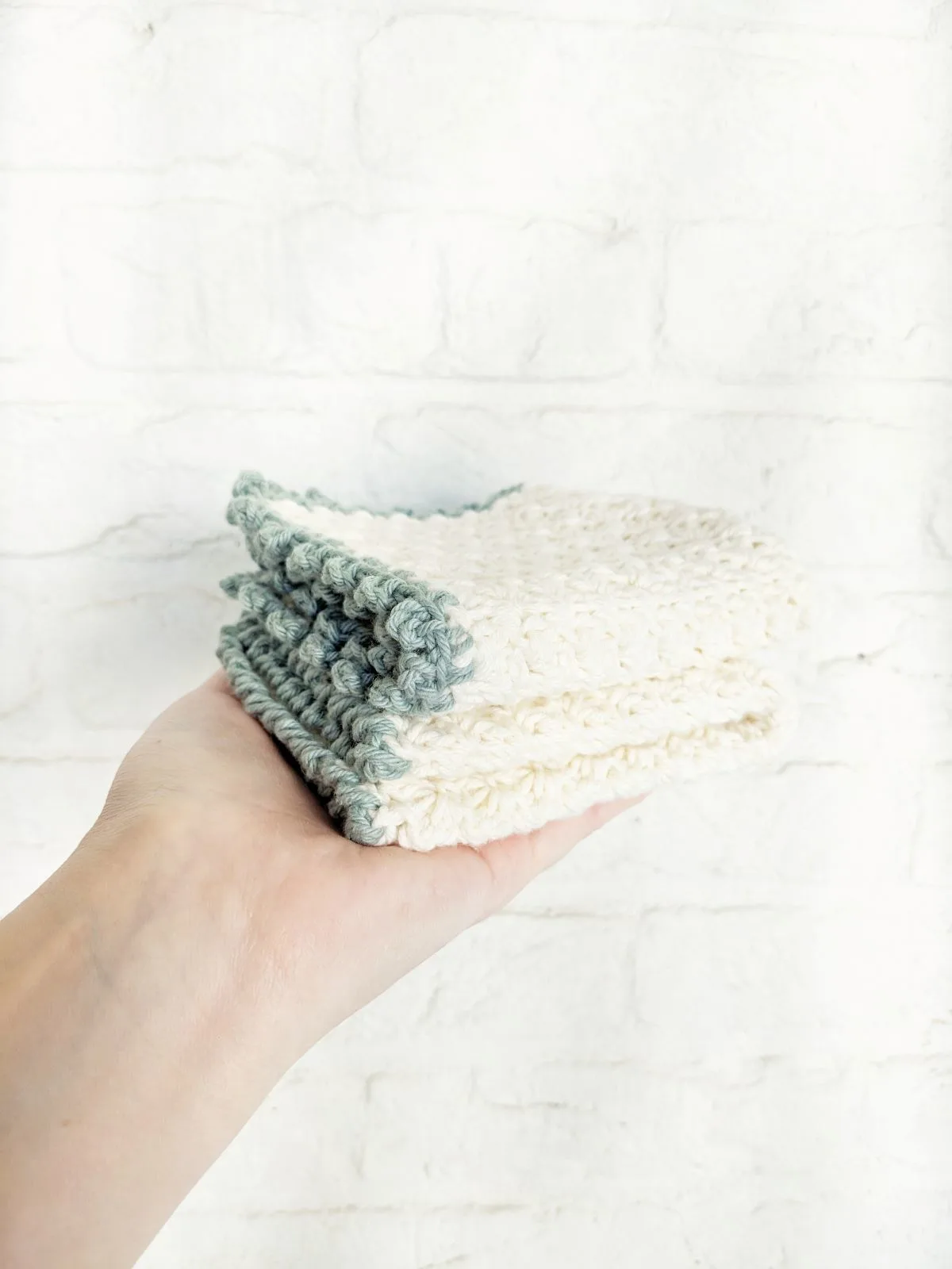 A crochet washcloth that uses the suzette stitch with a picot stitch border.