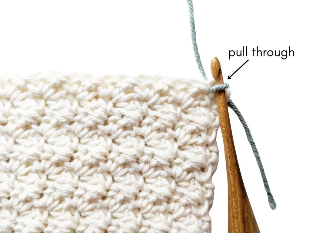 Pulling a new strand of yarn through a stitch.