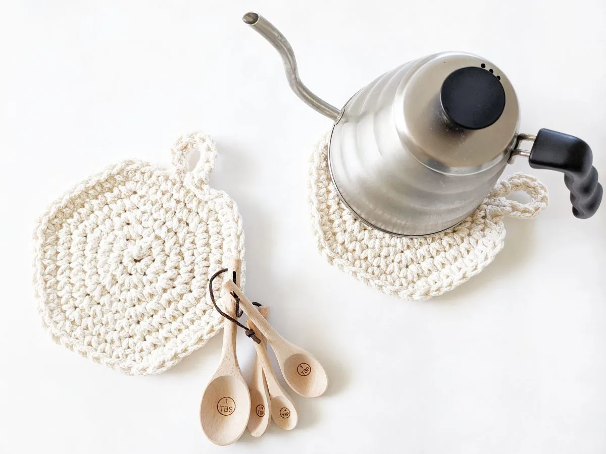 A round crochet hot pad with a tea kettle.