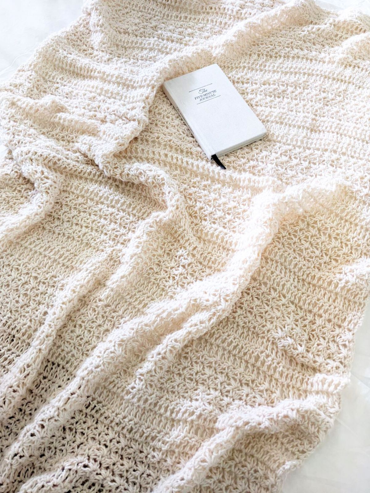 A modern crochet blanket with tons of texture on a bed.