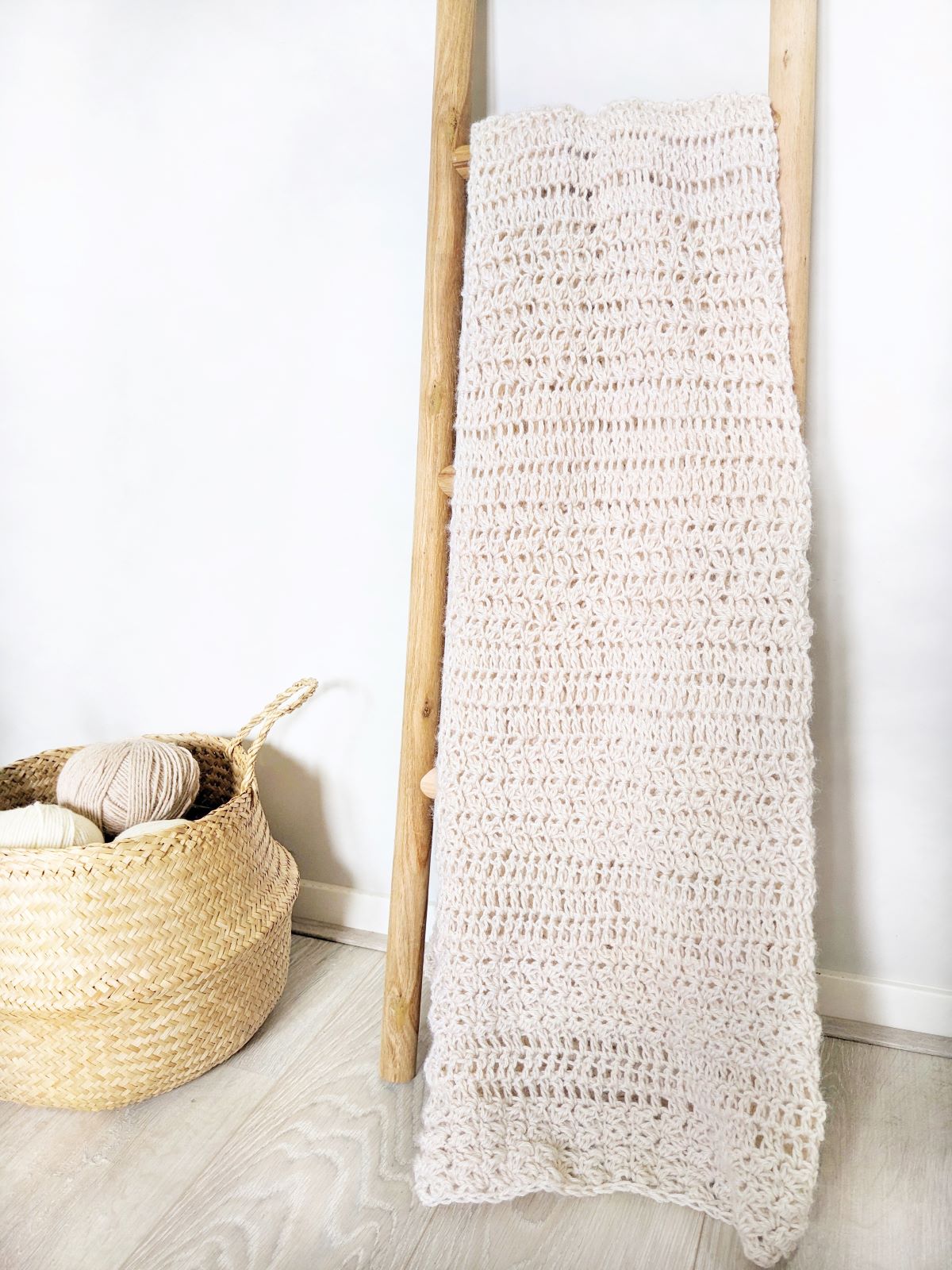 A large textured crochet blanket on a decorative ladder.