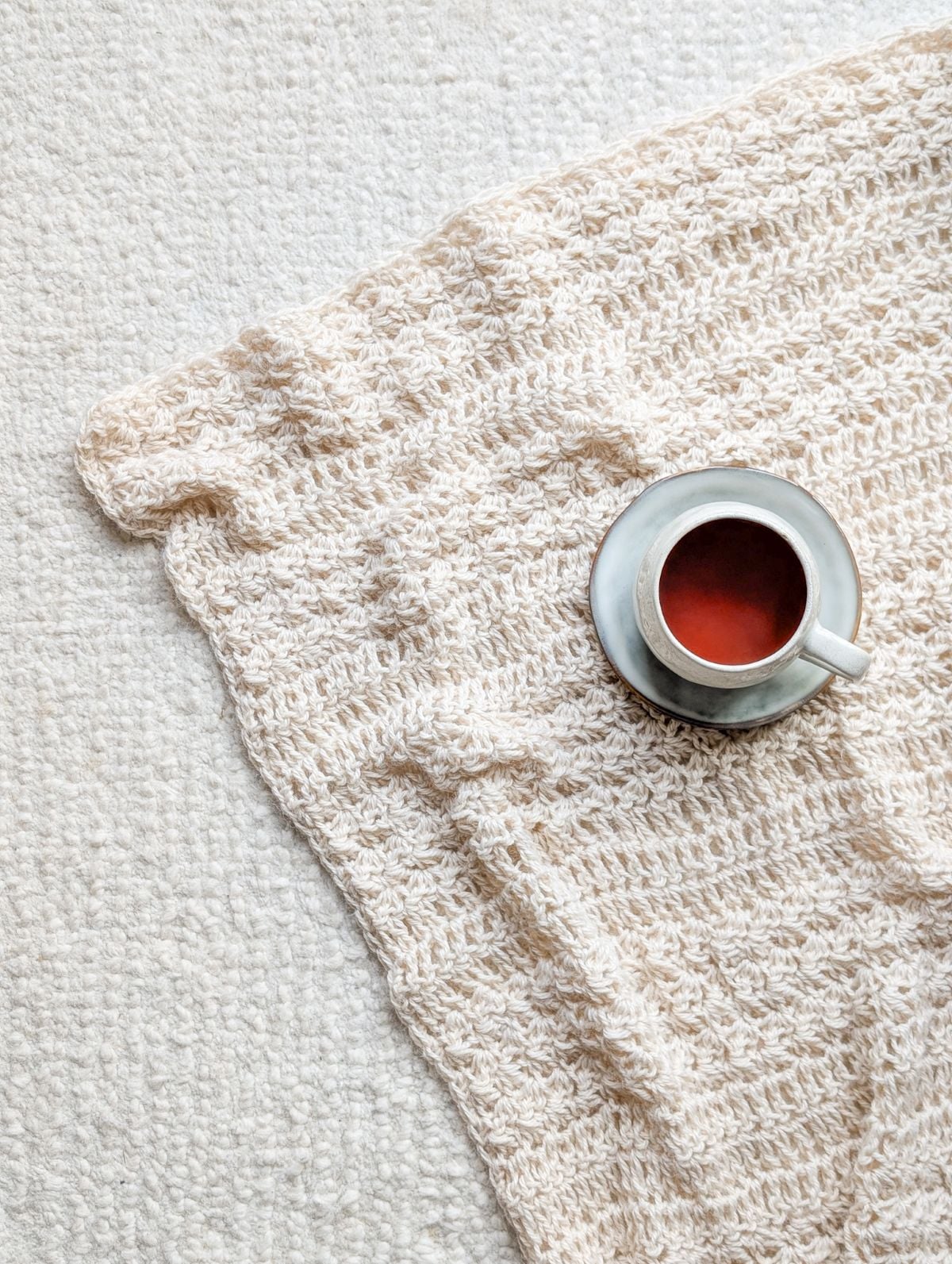 A crochet blanket on a white rug.