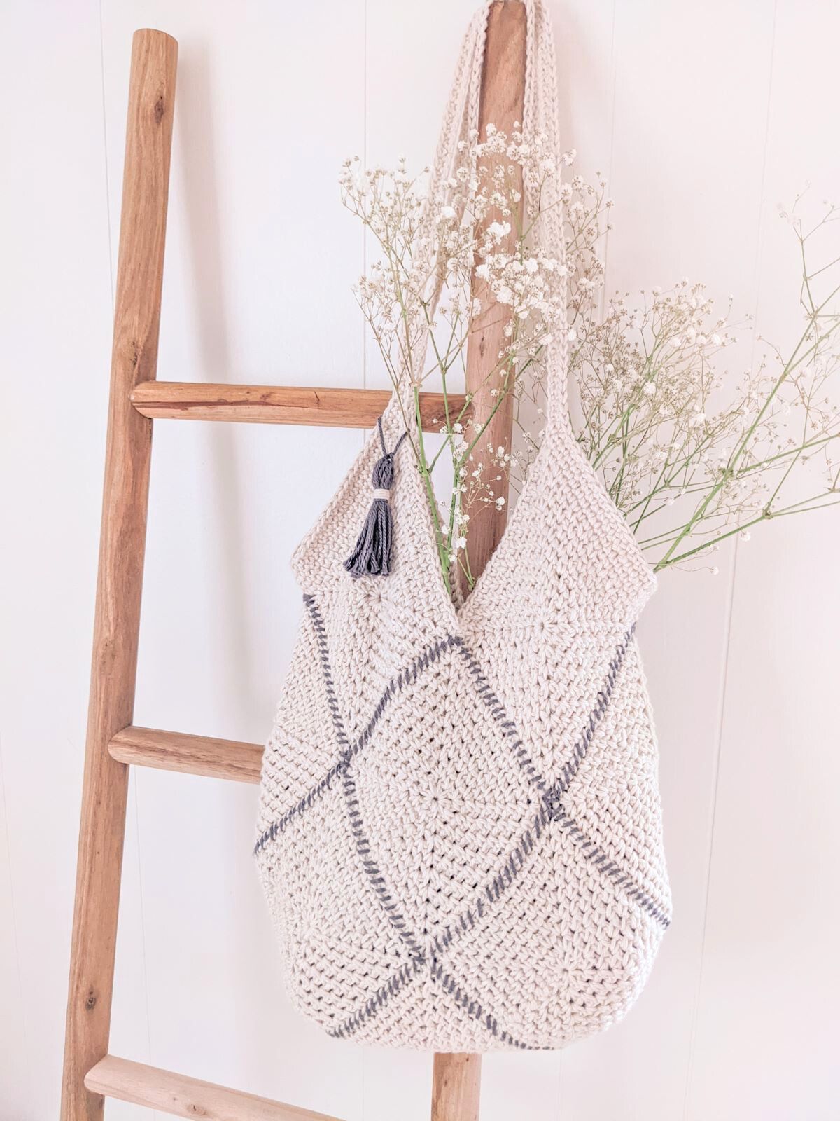 A traditional crochet granny square bag on a decorative ladder. 