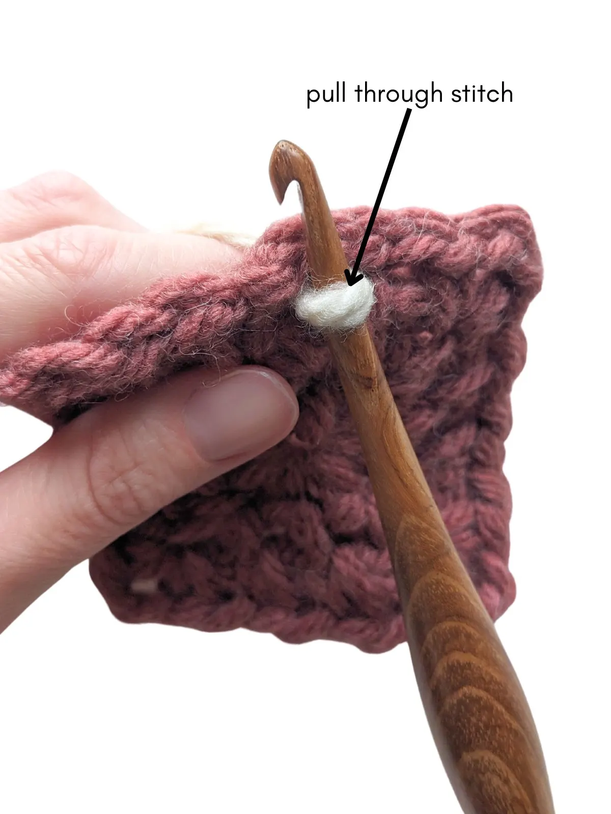 A crochet hook is being pulled through the stitch. 
