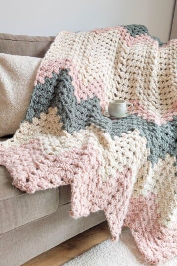 A chunky oversized chevron throw crochet blanket draped over a couch.