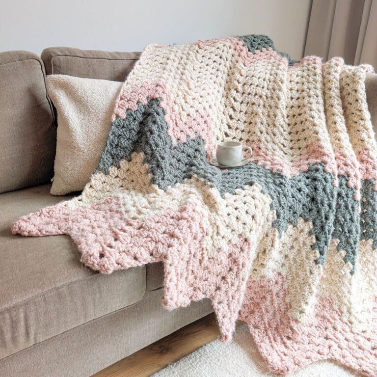 A chunky oversized chevron throw crochet blanket draped over a couch.