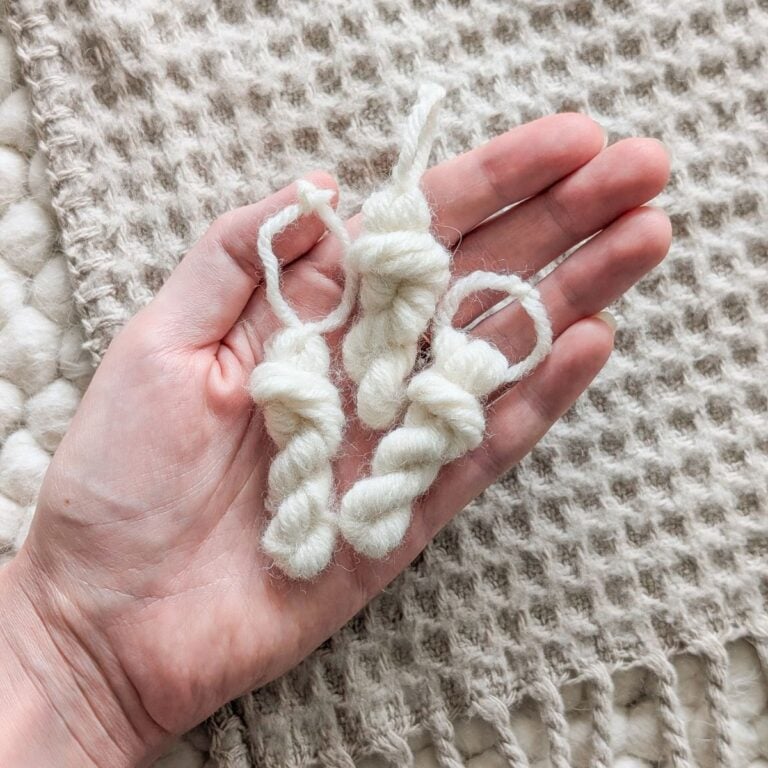 Three mini white yarn hanks made with worsted-weight yarn.