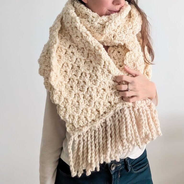 Model is wearing a chunky bulky-weight crochet blanket scarf in the color natural.
