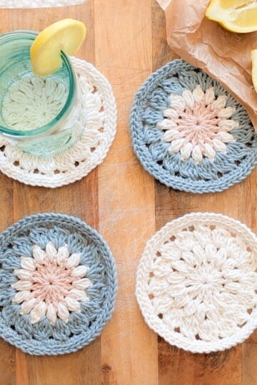 A crochet round coaster on a wooden block.