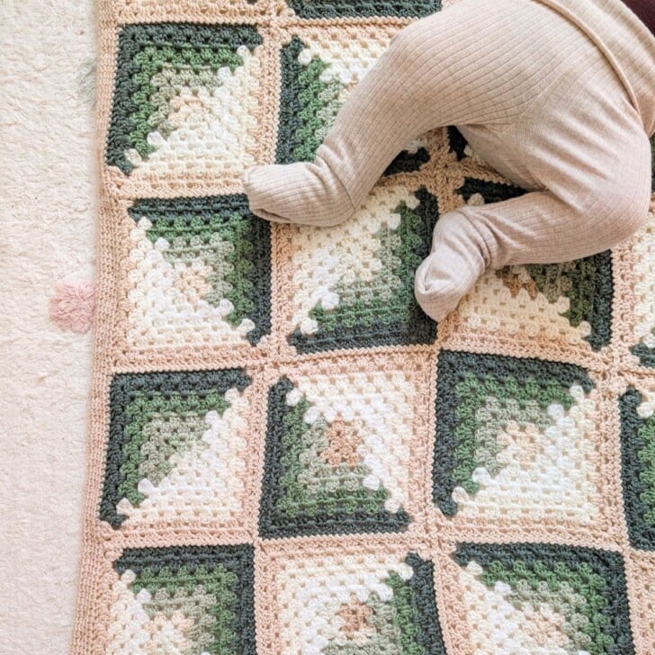 A granny square crochet baby blanket with a baby on it.