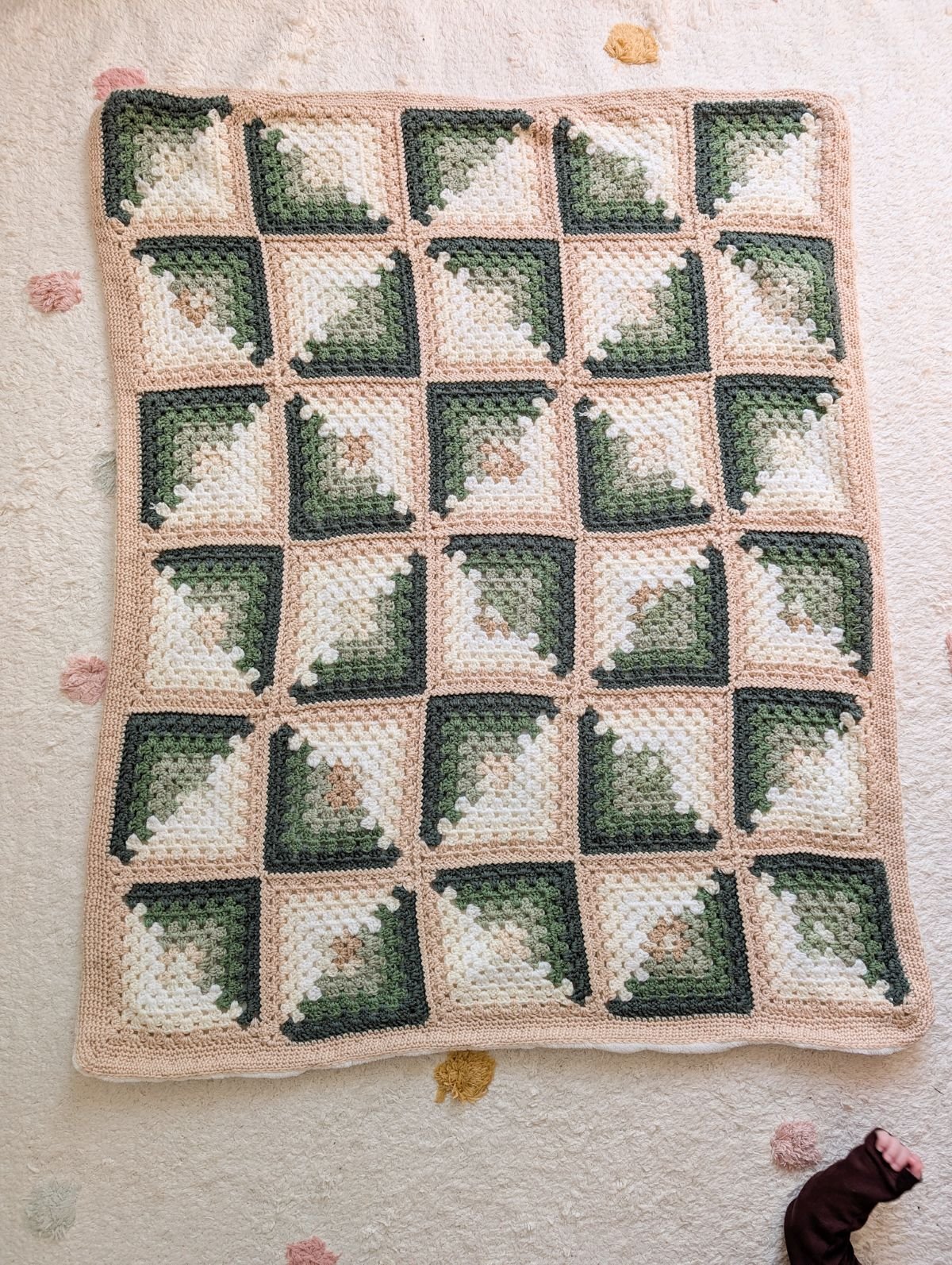 A colorful crochet baby blanket that is made with granny squares.