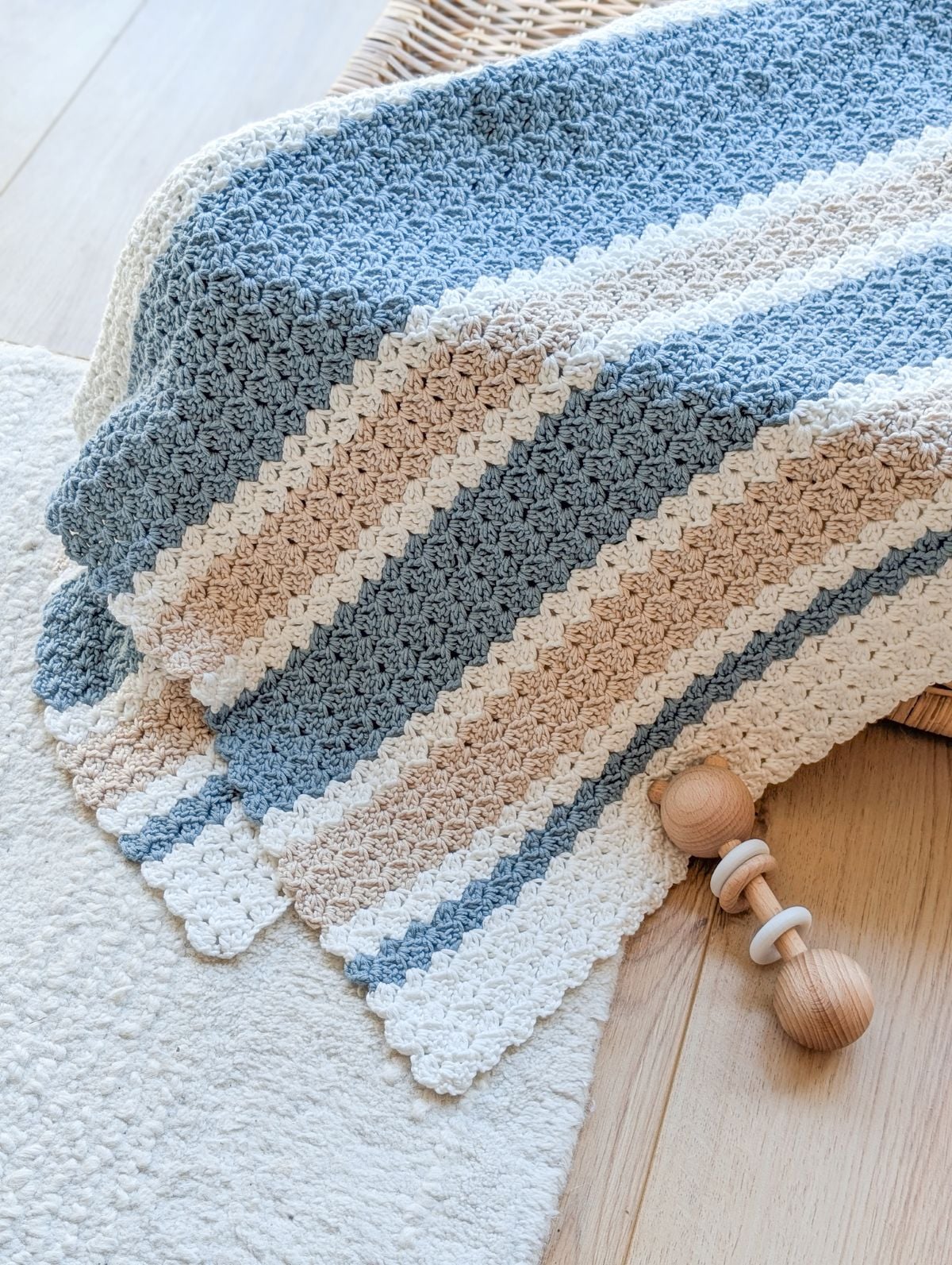 A folded 3 color crochet baby blanket on a box.