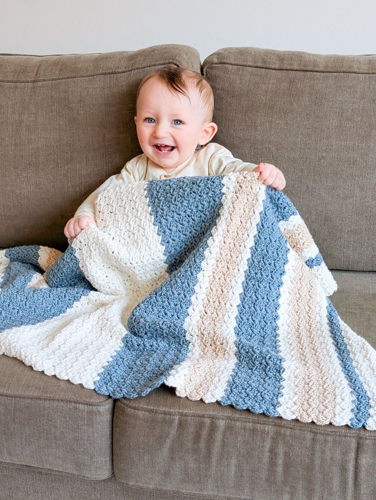 A baby holding a crochet baby blanket.