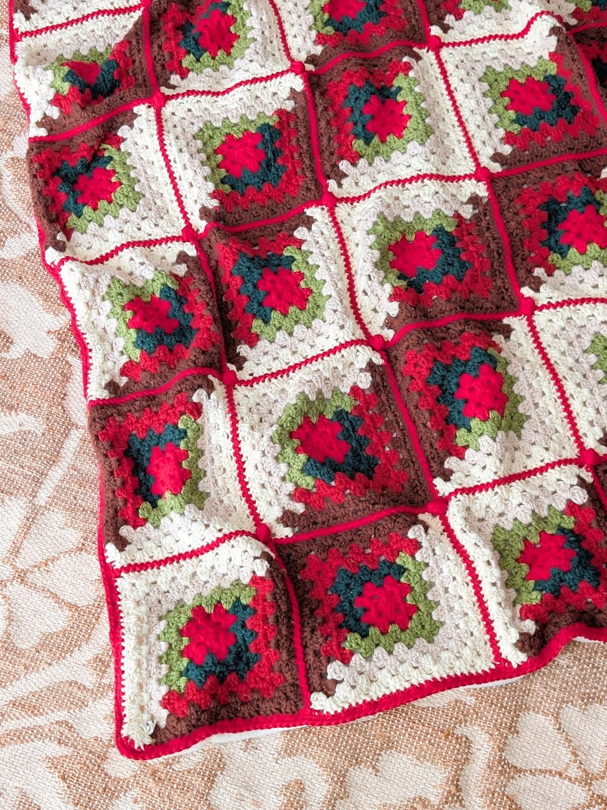 A crochet blanket on the floor in Christmas colors.