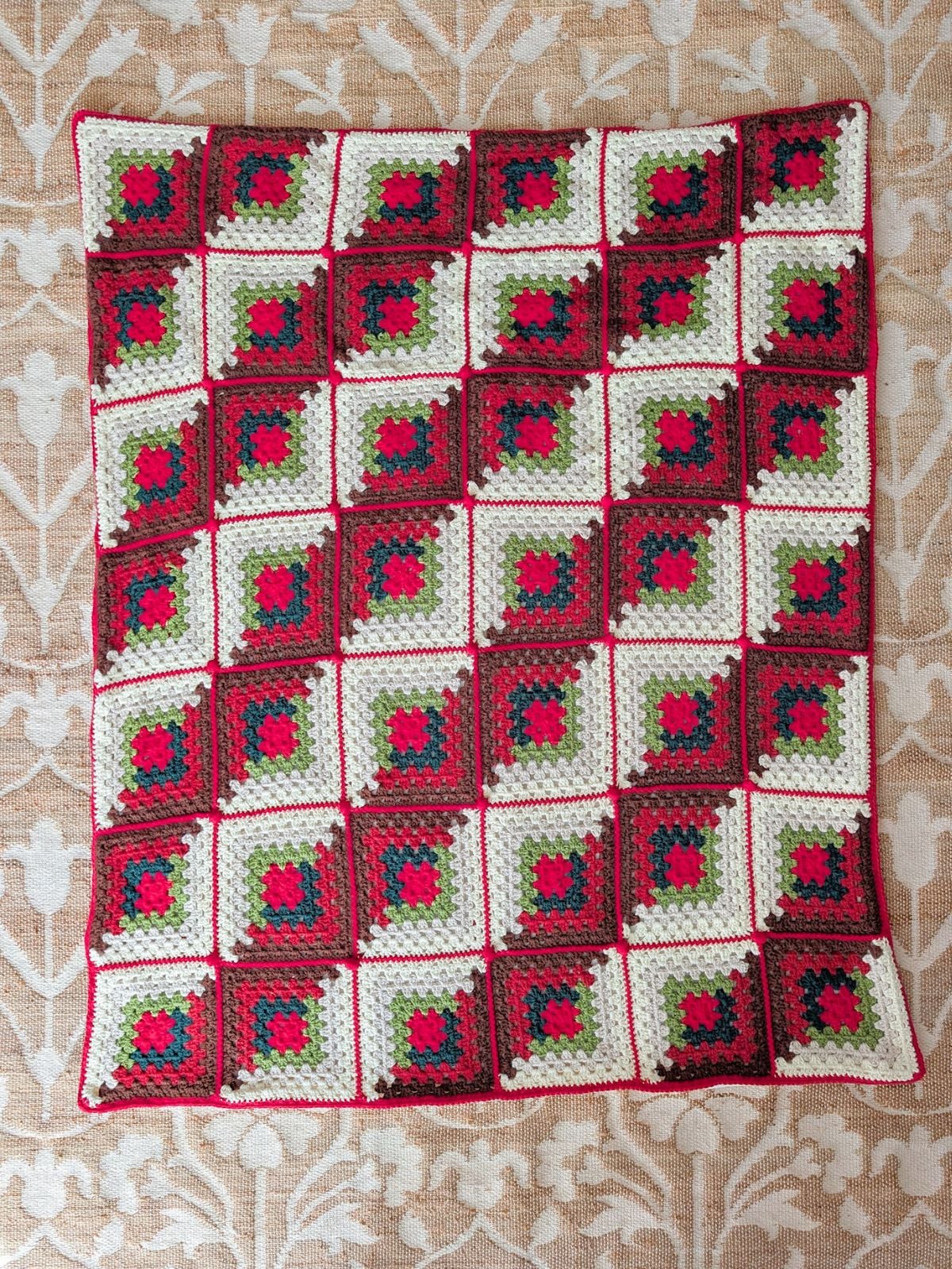 A large crochet granny square blanket in 7 different colors.