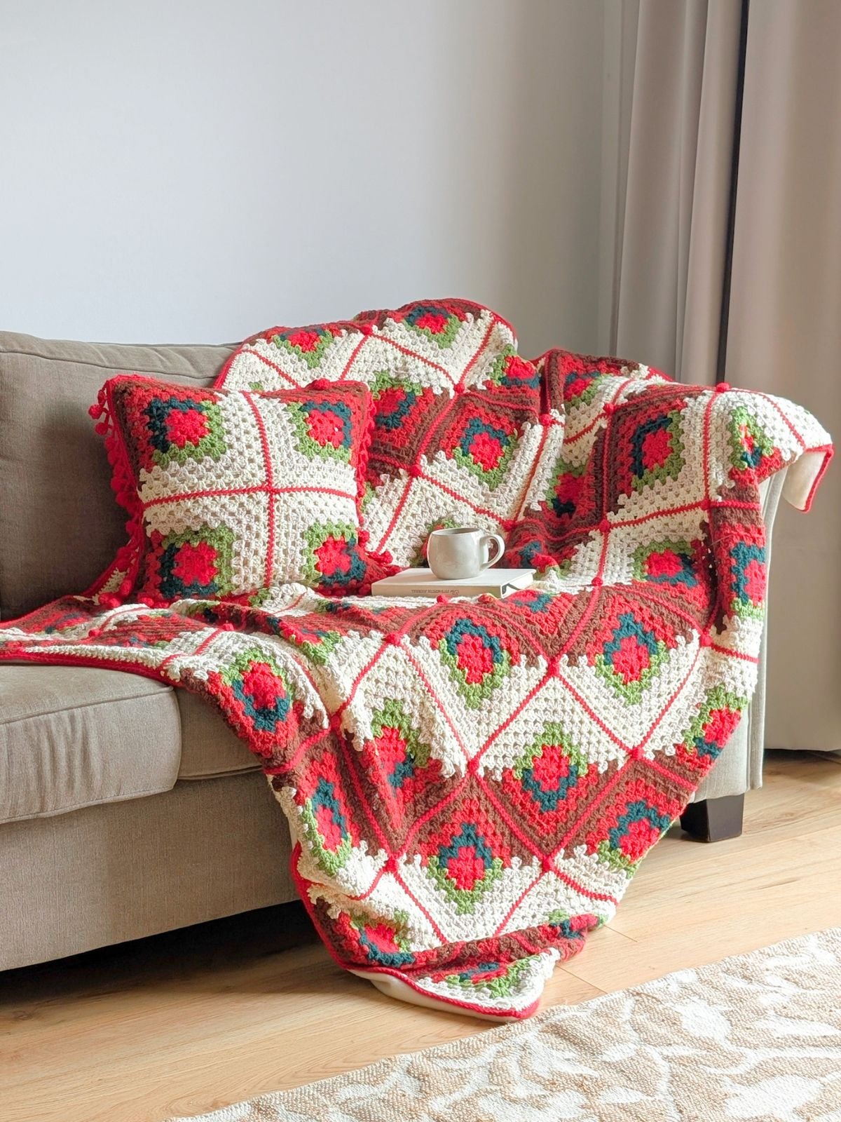 A matching crochet Christmas pillow and blanket on a couch.
